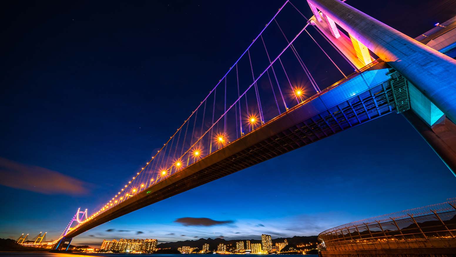 A city bridge at night time with colorful lights