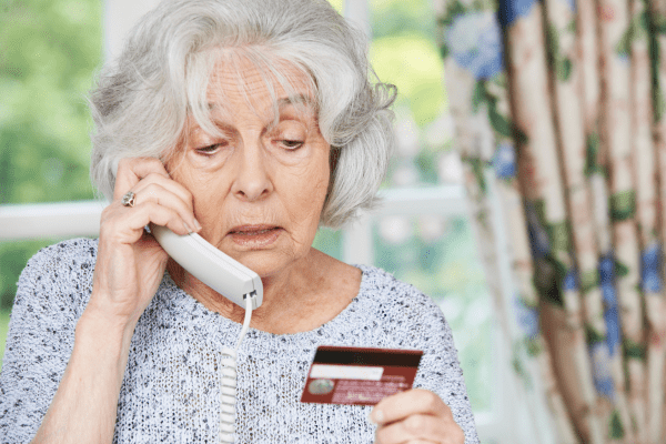 Senior Woman giving financial information over a landline phone