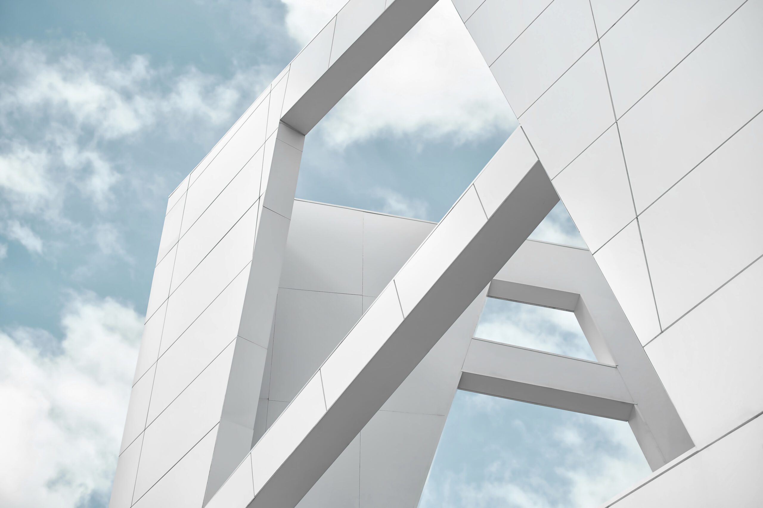 Big white walls of the building against the blue sky and white clouds. Modern architecture. Minimalistic design