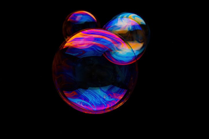Three colorful shiny soap bubbles floating on black background, macrophoto, studio shot