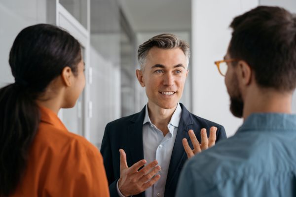 Male business exec talking to others represents outsourcing