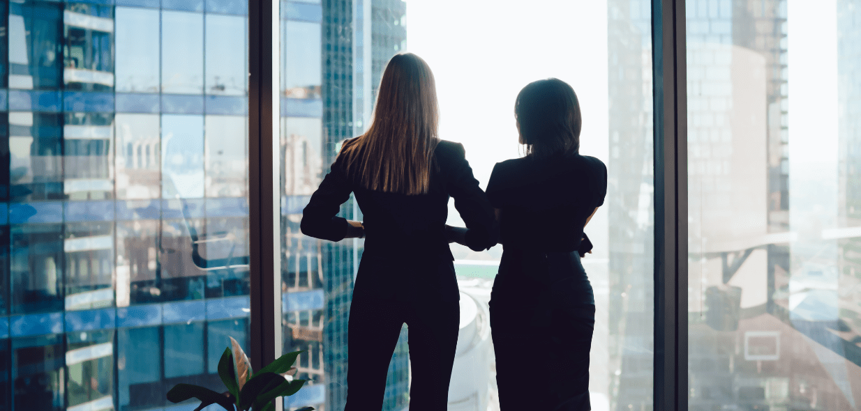 two women in business attire facing a window discussing types of outsourcing